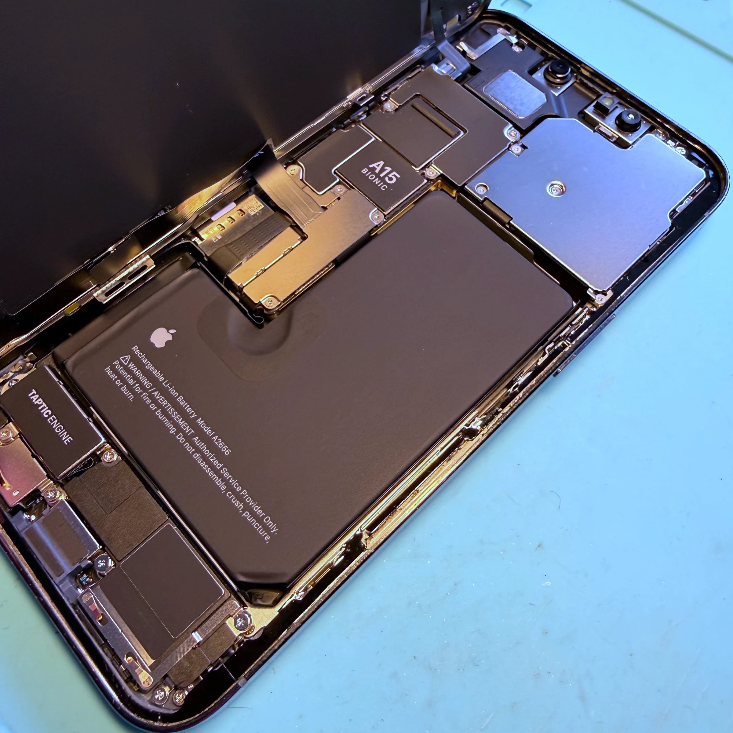 Öppnad iPhone med synligt batteri och moderkort under reparation hos NejNejWorkshop i Strängnäs